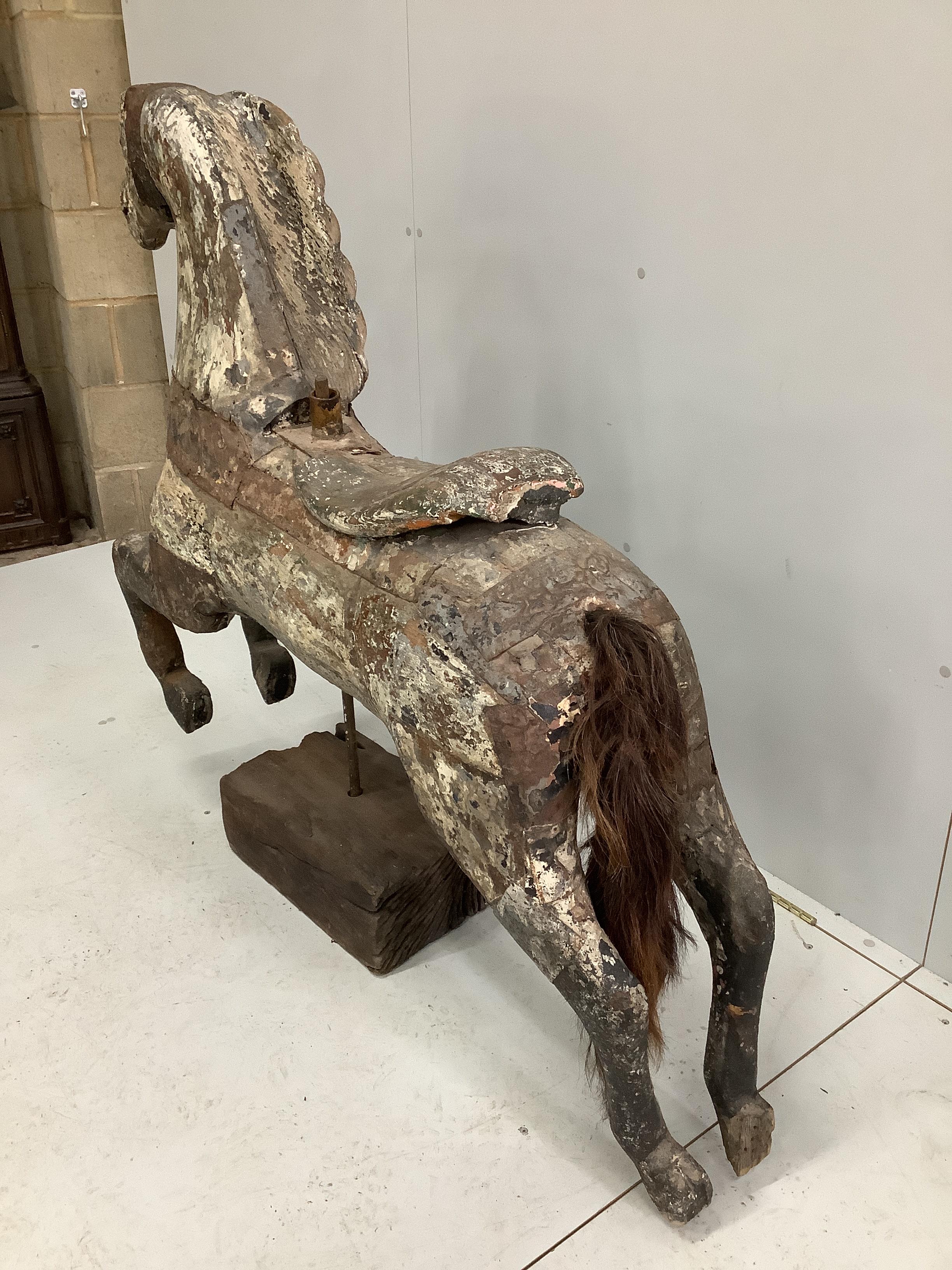 A vintage metal bound carved wood carousel fairground horse with traces of original paint, length 128cm, height 118cm